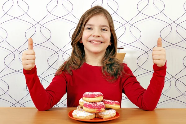 Niña feliz con donuts y pulgares hacia arriba — Foto de Stock