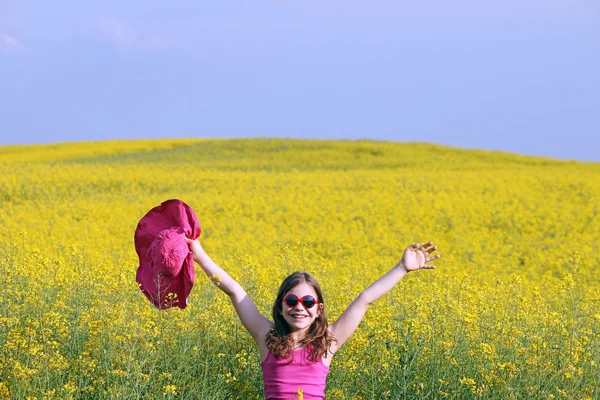 Little girl with hands up on yellow flowers field summer season — Stock Photo, Image