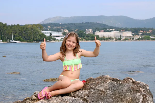 Счастливая маленькая девочка с большим пальцем вверх на летних каникулах — стоковое фото