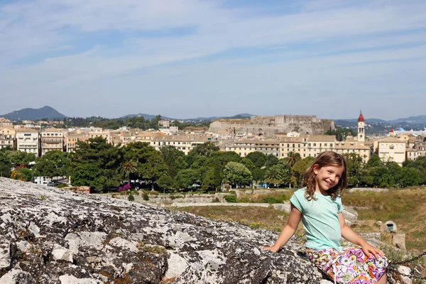 Happy little girl sitting on stone wall Corfu town — Stock Photo, Image