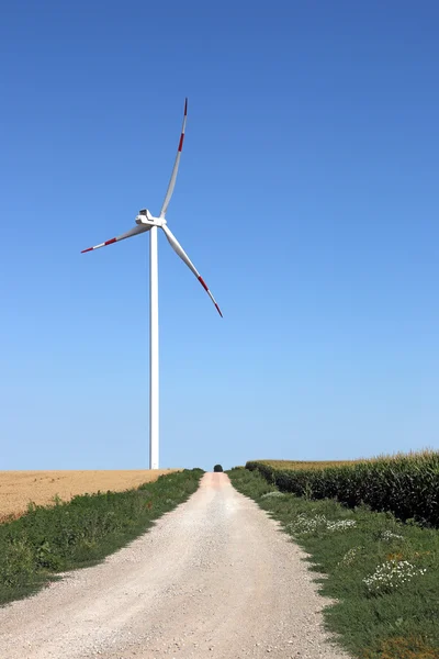 Turbina eólica no campo com estrada do país — Fotografia de Stock