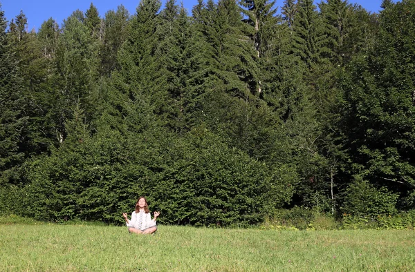 Menina meditando na frente da floresta — Fotografia de Stock