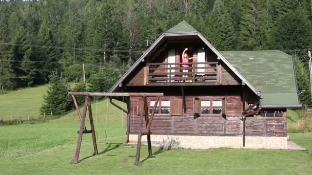 Šťastná holčička mává z dřevěných chatrčí balkón — Stock video