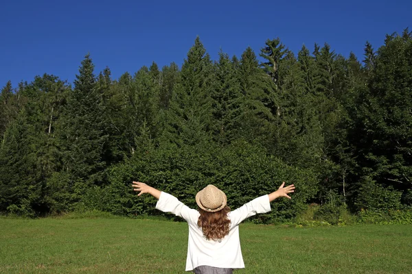 Meisje met handen omhoog kijken naar het bos — Stockfoto