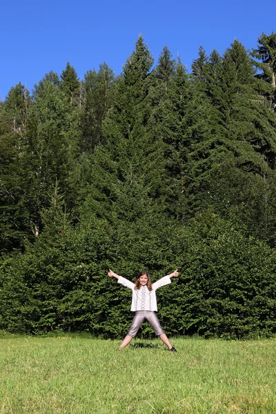 Heureuse petite fille avec les pouces debout en face de la forêt — Photo