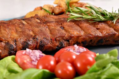 Domuz pirzolası, patates ve domates tabakta.