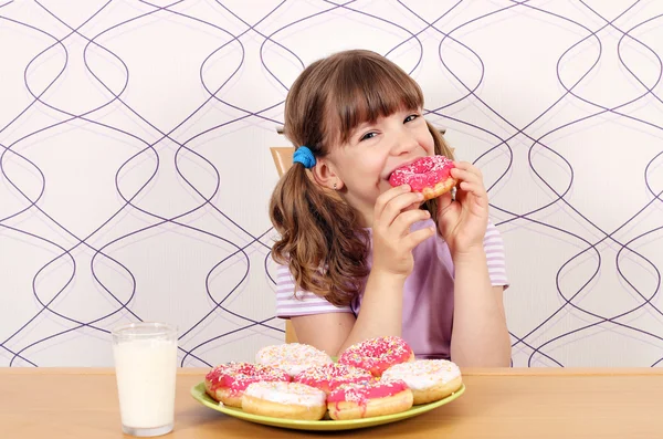 Hladová malá holčička jíst sladké koblihy — Stock fotografie