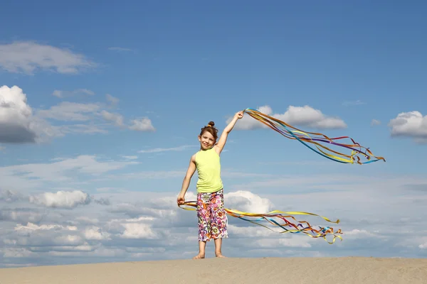 Niña feliz saludando con cintas de colores en el desierto — Foto de Stock