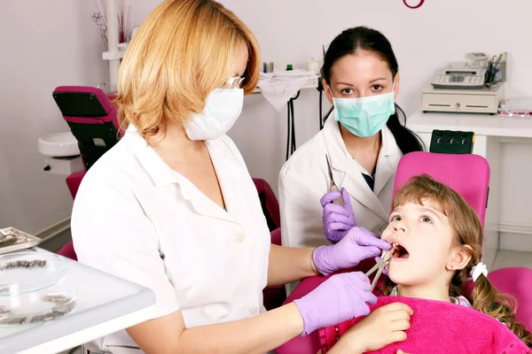 Dentista enfermera y niña pequeña paciente en el consultorio dental — Foto de Stock