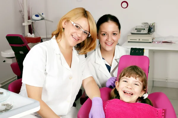 Glückliche kleine Patientin mit Zahnarzt und Krankenschwester — Stockfoto