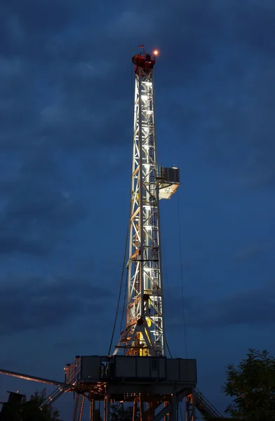 Equipamento de perfuração de petróleo terrestre iluminado — Fotografia de Stock