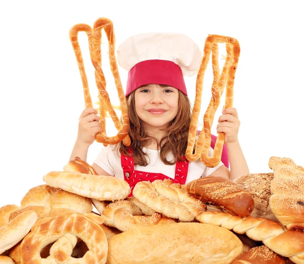 Klein meisje kok met gebak pretzels en broden — Zdjęcie stockowe