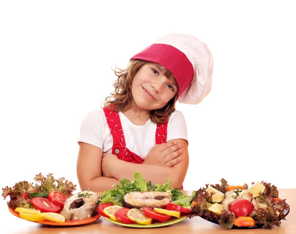 Heureuse petite fille cuisinier avec du saumon fruits de mer — Photo