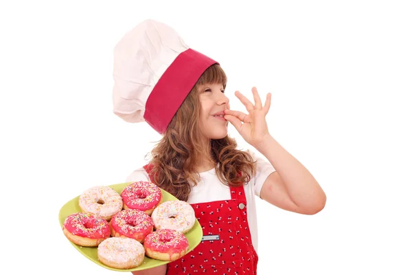 Kleines Mädchen kocht mit süßen Donuts und ok Handzeichen — Stockfoto