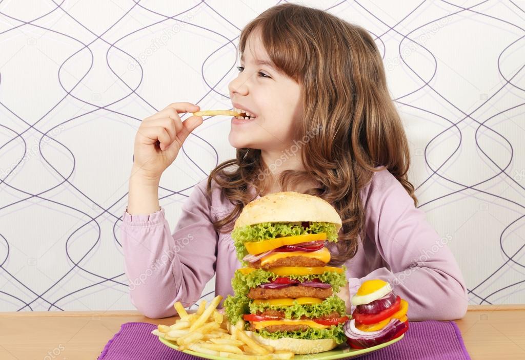hungry little girl eat french fries and big hamburger