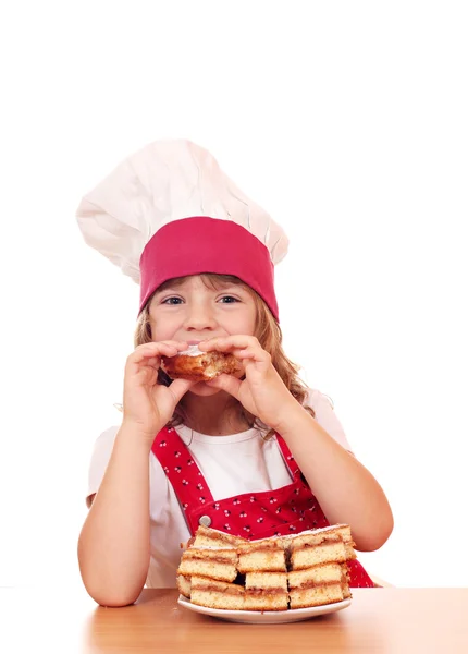 Hungry little girl cook eating apple cake — Stock Photo, Image