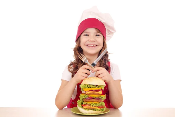 Little girl cook with big hamburger on table — Stock Photo, Image
