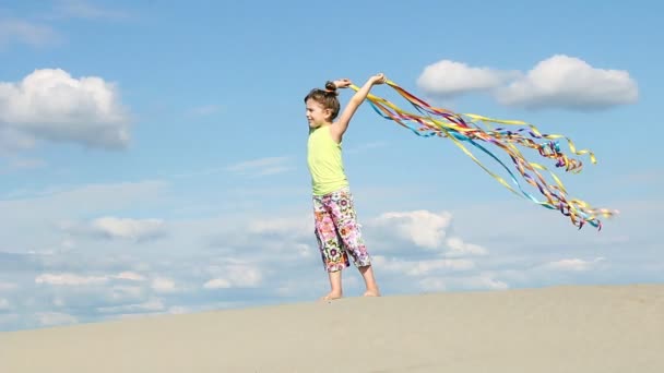 Kislány a színes szalagok, a szeles strandon — Stock videók