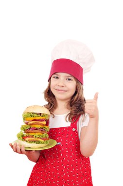 mutlu küçük kız yemek büyük hamburger ve başparmak ile