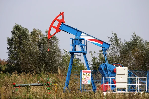 Oil pump jack on windy field — Stock Photo, Image