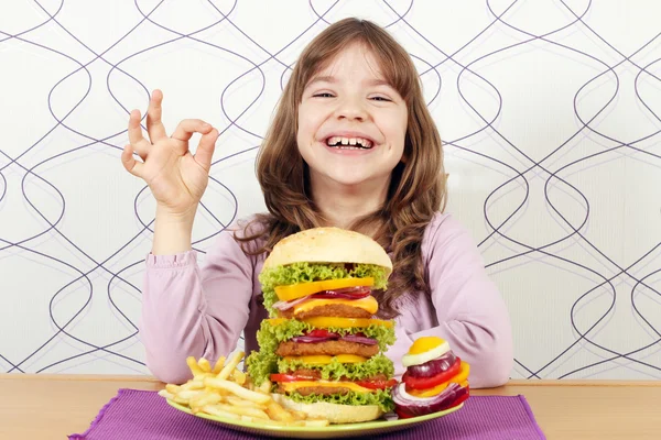 Gelukkig meisje met grote hamburger en ok hand teken — Stockfoto