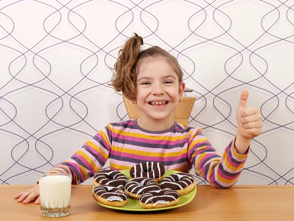 Menina feliz com donuts de chocolate e polegar para cima — Fotografia de Stock