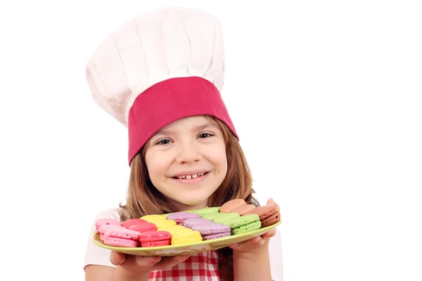 Little girl cook hold plate with macarons — Stock Photo, Image