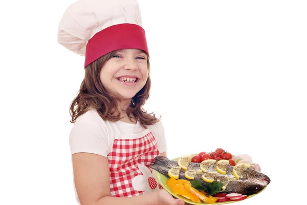 Gadis kecil bahagia memasak dengan trout di piring — Stok Foto