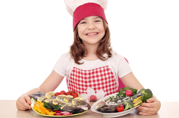 Menina feliz cozinhar com peixes preparados — Fotografia de Stock