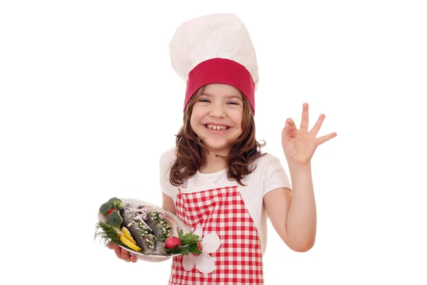 Happy little girl cook with fish and ok hand sign — Stock Photo, Image