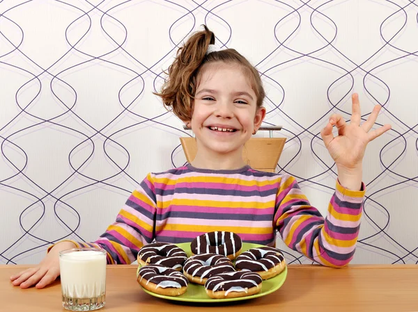 Šťastná holčička s ok ruční znamení a čokoládové koblihy — Stock fotografie