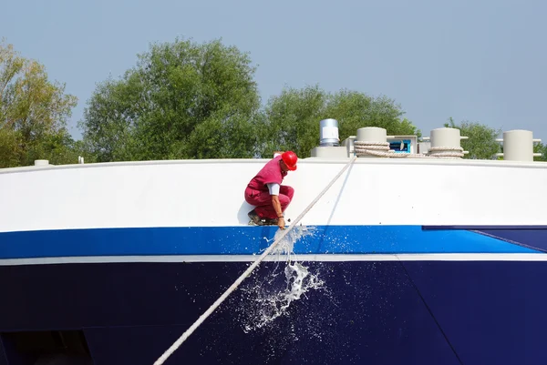 Worker smashing a bottle of champagne on the new ship — Stock Photo, Image