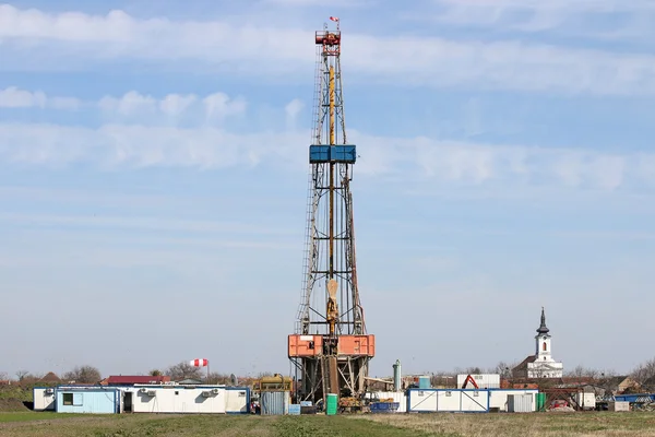 Land olieboringen tuig met werknemers in de buurt van dorp — Stockfoto