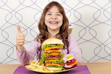 büyük hamburger ve başparmak ile mutlu küçük kız