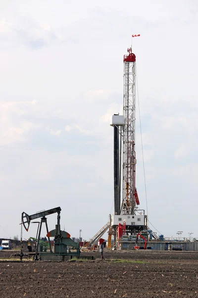 Pump jack and land oil drilling rig on oilfield — Stock Photo, Image