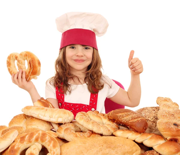 Happy little girl cook with pretzel and thumb up — Stock Photo, Image