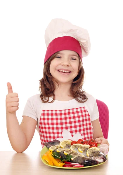 Heureuse petite fille cuisinier avec truite et pouce vers le haut — Photo