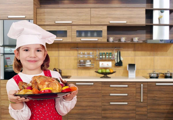 Petite fille cuisinier avec poulet dans la cuisine — Photo