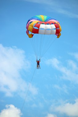 İki kişi mavi gökyüzü bulutlu paraşüt ile parasailing