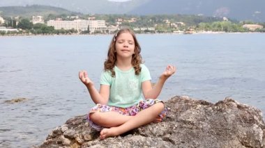 küçük kız bir kaya denizin kenarında oturan ve derin derin düşünür