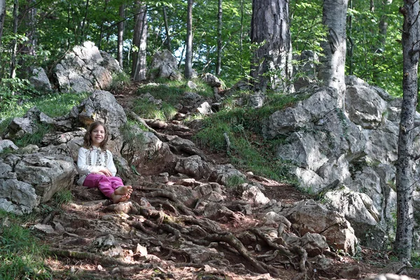 Счастливая маленькая девочка, сидящая в лесу — стоковое фото