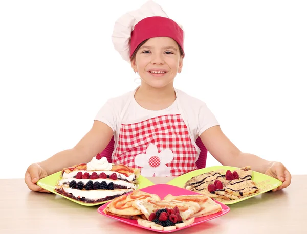 Happy little girl cook with delicious crepes on table — Stock Photo, Image