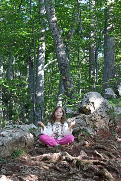 Beautiful little girl meditating in the forest — Stock Photo, Image