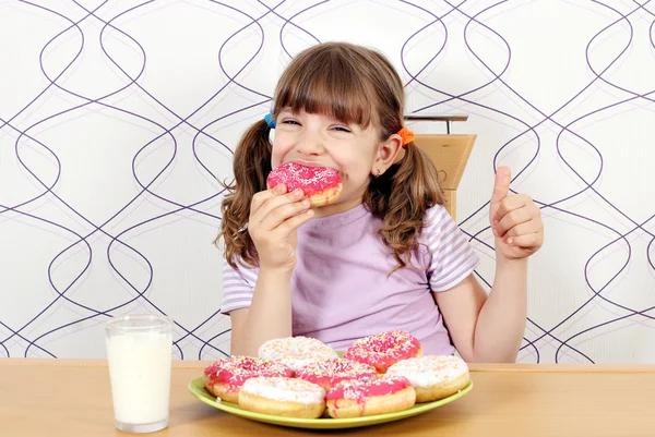 Hungrig liten flicka äta munkar — Stockfoto