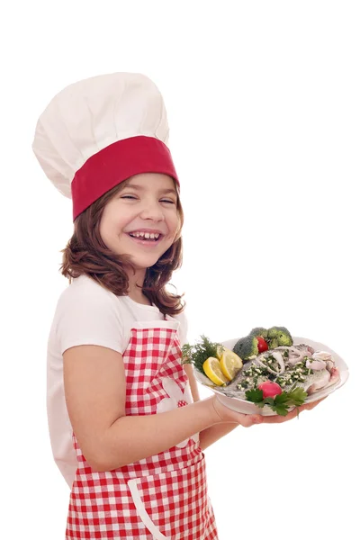 Feliz niña cocinera con trucha fresca en el plato —  Fotos de Stock