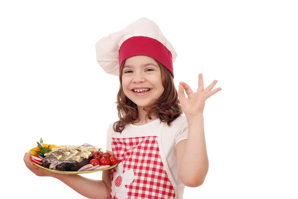 Menina feliz cozinhar com peixe de truta e sinal de mão ok — Fotografia de Stock