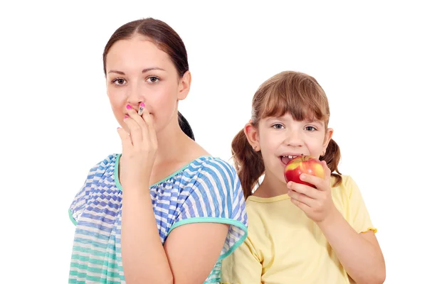 Dívka s cigaretou a holčička jíst jablko unhea — Stock fotografie