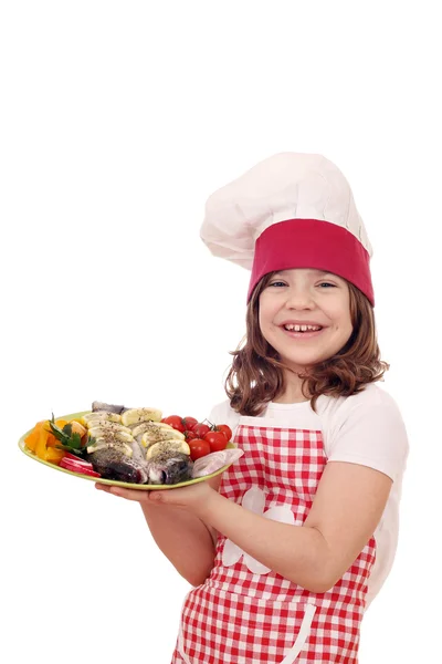 Happy little girl cook with trout fish on plate — Stock Photo, Image