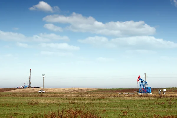 Oil pump jack and land drilling rig on field — Stock Photo, Image
