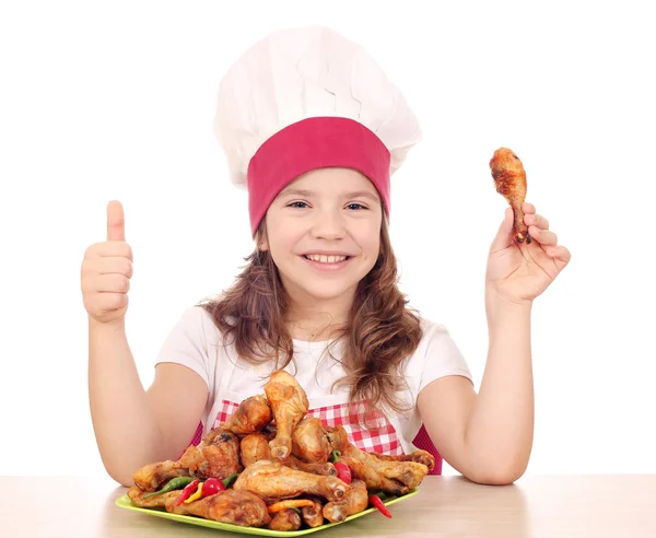 Feliz niña cocinero con el muslo de pollo y pulgar hacia arriba —  Fotos de Stock